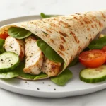 Grilled chicken Caesar wrap on a wooden plate with fresh vegetables.chicken Caesar wrap Calories