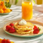 A brunch platter featuring high-protein pancakes served with fresh juice and fruit.