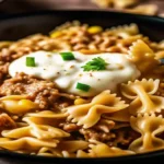 Close-up of a creamy ranch beef bowtie pasta skillet with sweet corn, garnished with fresh parsley and a dollop of seasoned sauce, served in a black pan.Creamy Ranch Beef Bowtie Skillet with Sweet Corn Magic