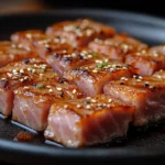 Seared ahi tuna slices with a golden crust on a dark plate.